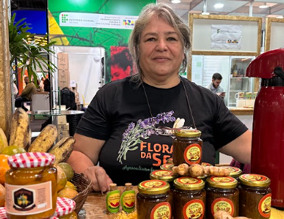 Mulher em feira, apresentando produtos à base de gengibre, o quentão no pote