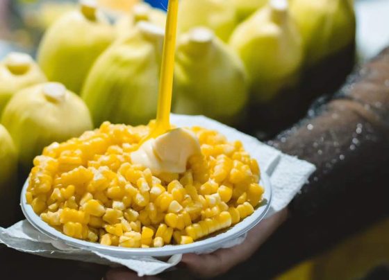 Pote de milho à frente e espigas em segundo plano