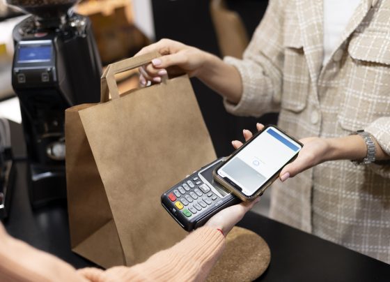 Imagem mostra pessoa usando o smartphone para pagar comprar; comércio, varejo